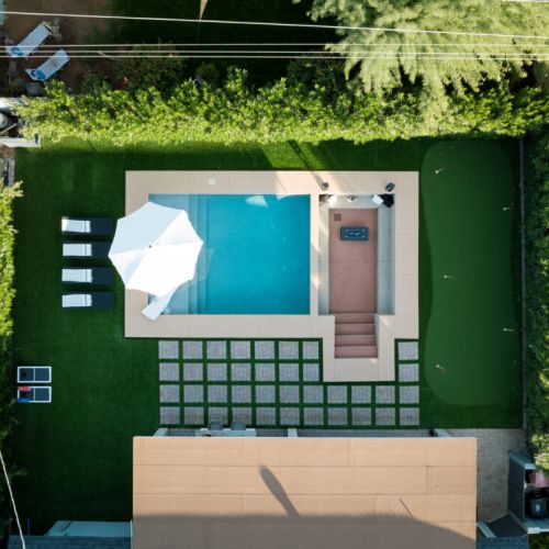 Birds-eye view of the crystal-clear pool and in-ground seating area with fire pit.