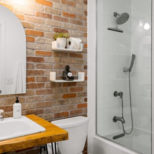 Secondary bathroom with tub/shower combo, original brick exposed wall for a touch of whimsy