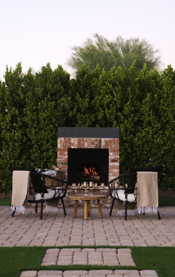 Wood-burning fireplace with a mature wall of greenery as the backdrop.