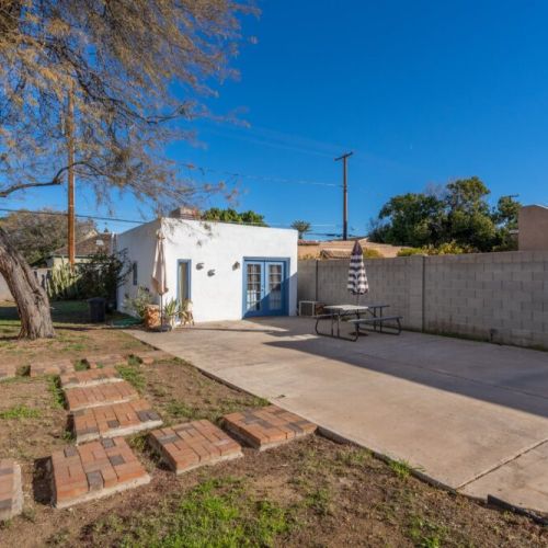 Spacious yard  with charming brick pathways and a cozy seating area, ideal for relaxing or entertaining under the sun.