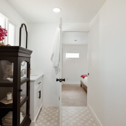 Soft lighting and clean lines carry into the hallway, leading from the bedroom to the tranquil bathroom space.